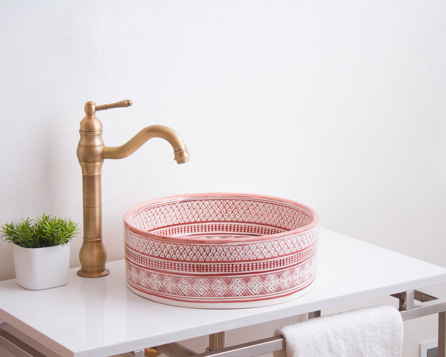 Round Moroccan ceramic basin installed on white bathroom vanity with traditional brass faucet and decorative plant