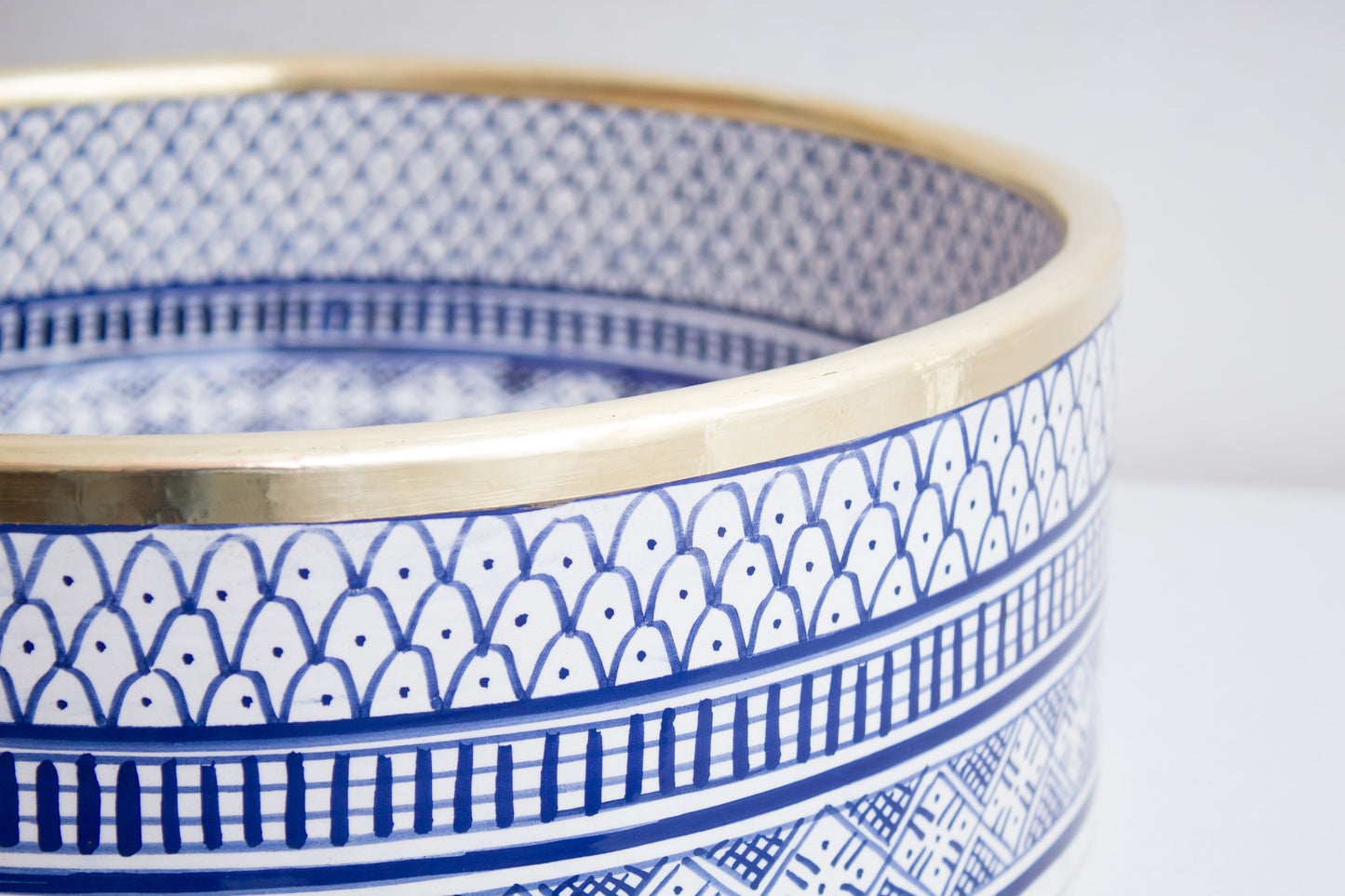 Macro close-up detail of intricate blue and white geometric pattern bands around the exterior rim of handcrafted ceramic basin