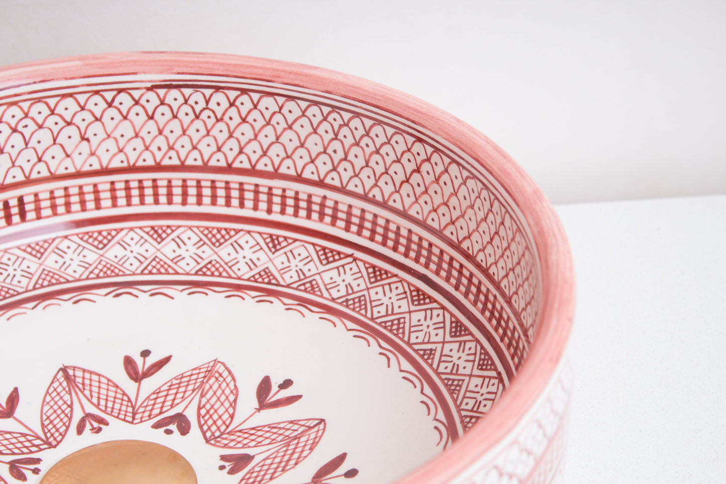 Angled interior view of Moroccan ceramic sink showcasing coral pink geometric border patterns and central floral motif design