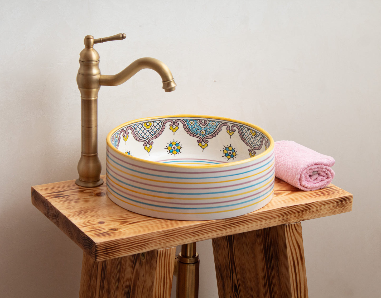 Ceramic sink installation example on wooden vanity with brass faucet and towel accessories