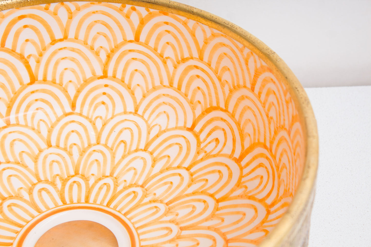 Close-up of intricate orange and white geometric mandala pattern hand-painted inside ceramic vessel sink