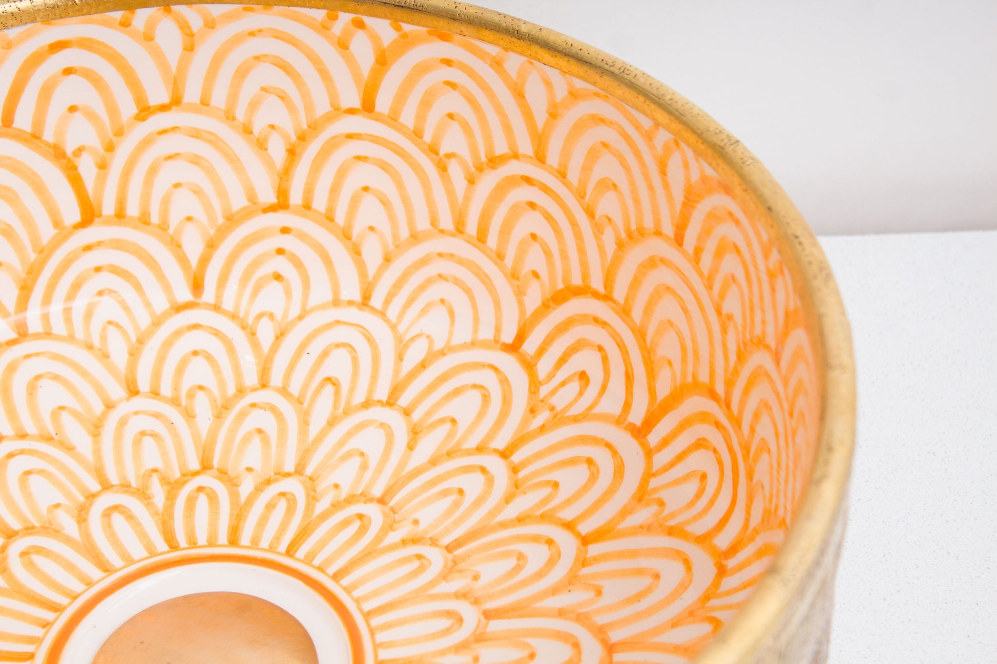 Close-up of intricate orange and white geometric mandala pattern hand-painted inside ceramic vessel sink