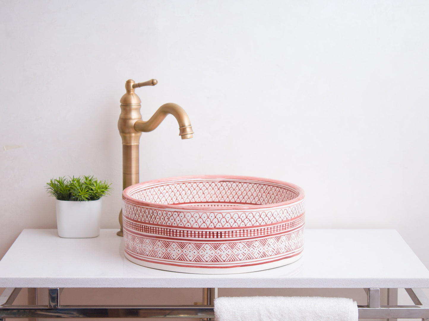 Side profile view of round ceramic vessel sink showing coral pink geometric pattern bands and bathroom installation