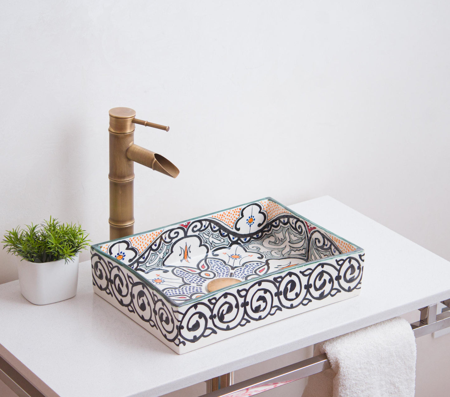 Artisanal ceramic vessel sink featuring intricate geometric patterns and orange accents positioned on modern bathroom vanity with brass fixtures