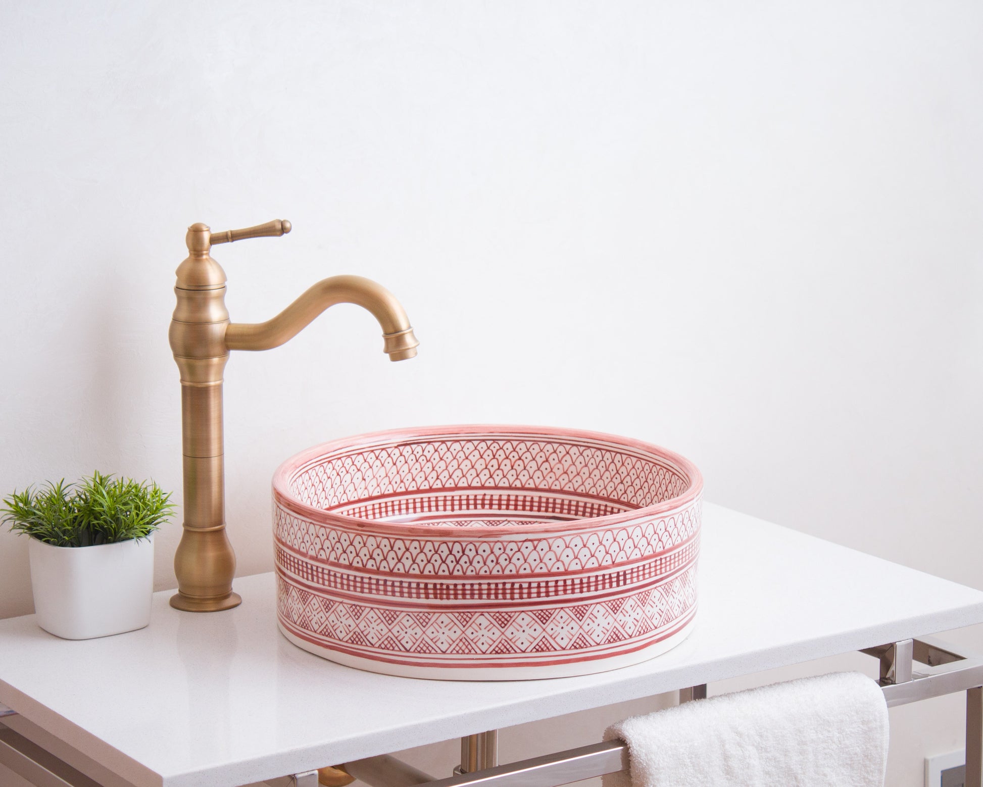 Round Moroccan ceramic basin installed on white bathroom vanity with traditional brass faucet and decorative plant