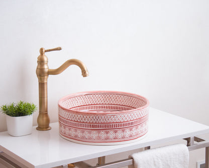Round Moroccan ceramic basin installed on white bathroom vanity with traditional brass faucet and decorative plant