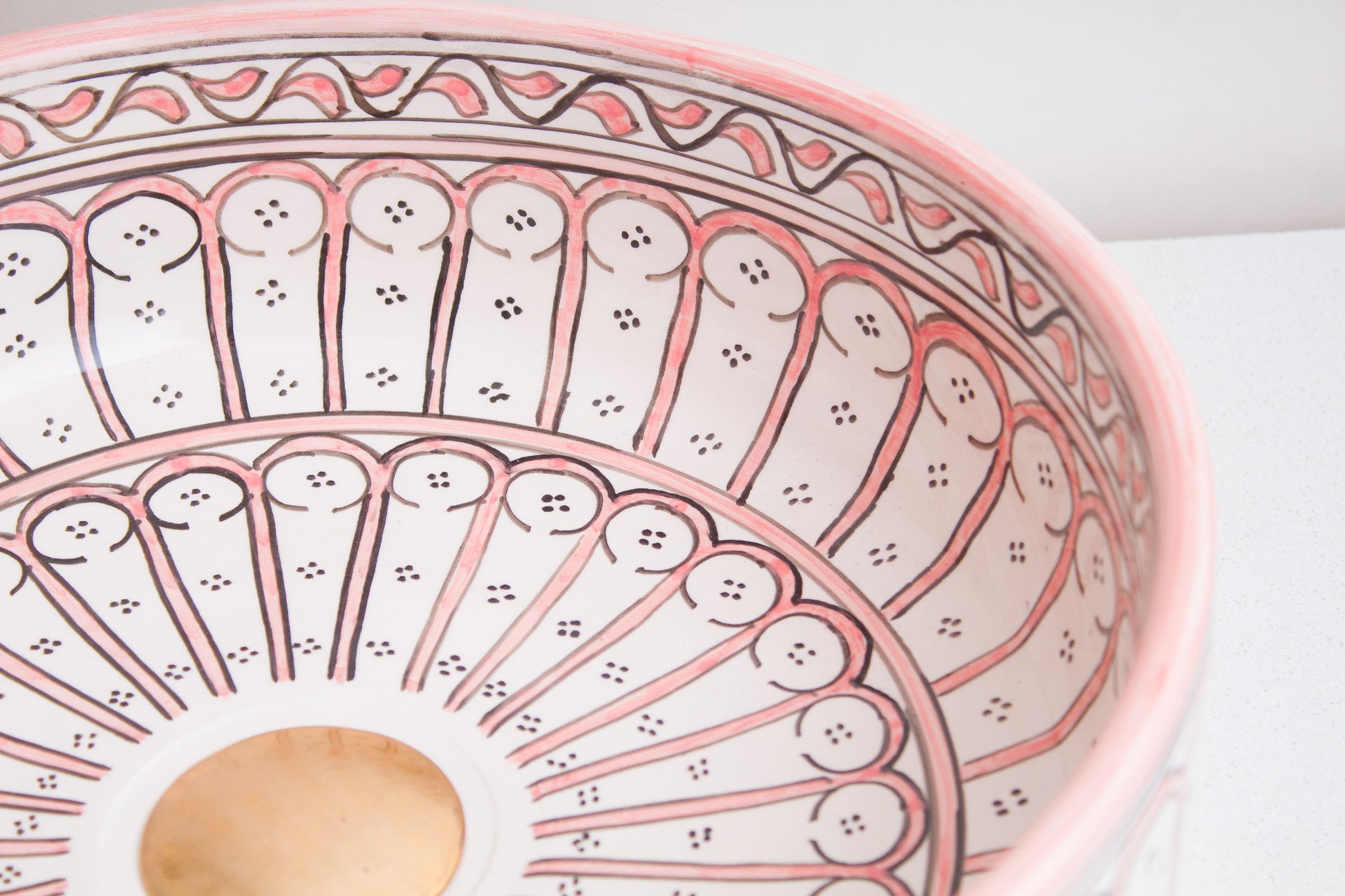 Angled interior view of Moroccan ceramic sink showcasing coral pink geometric arch border patterns and central radial design