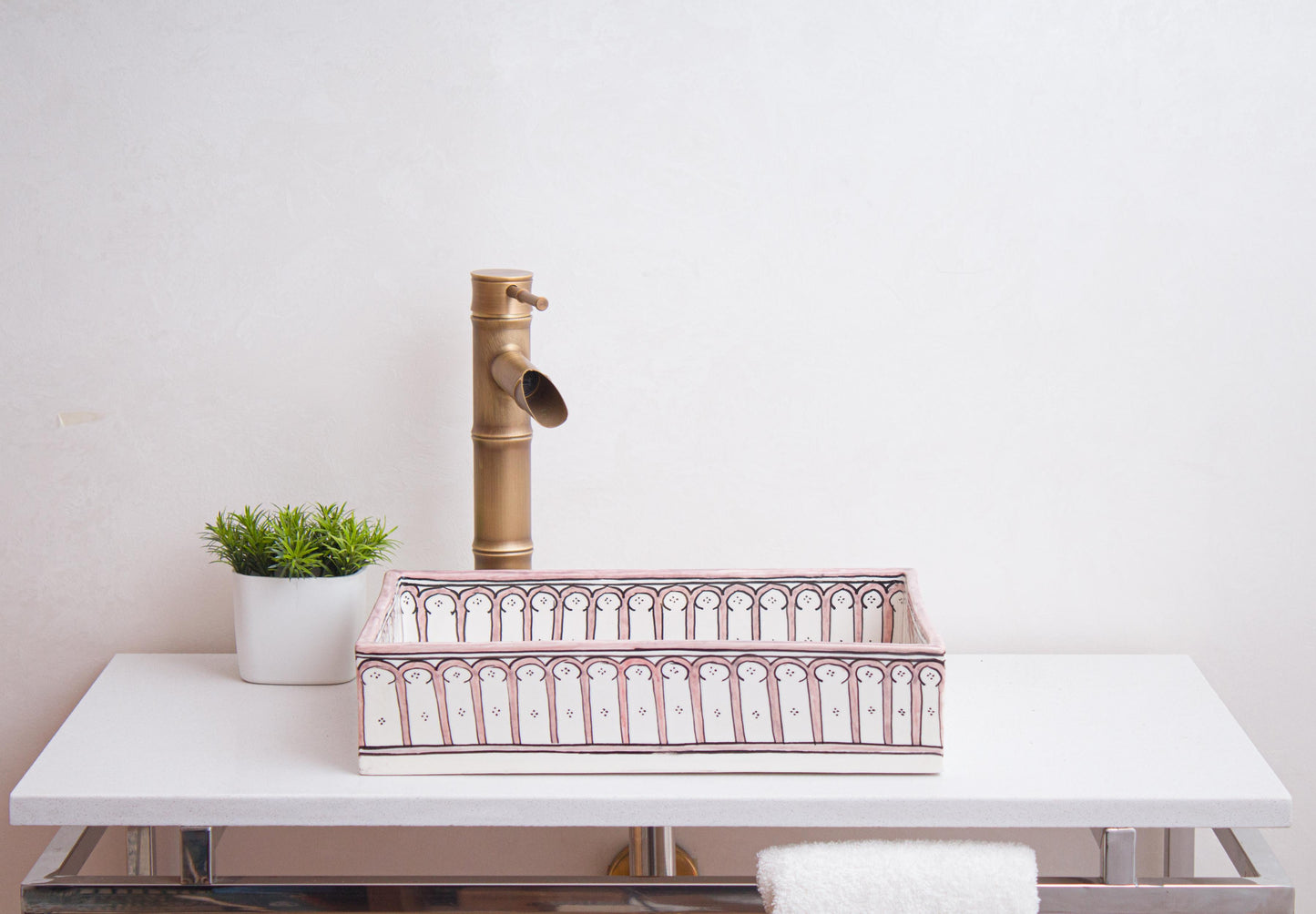 Side view of handmade rectangular ceramic sink showcasing pink arch colonnade border in bathroom setting with bamboo-style faucet