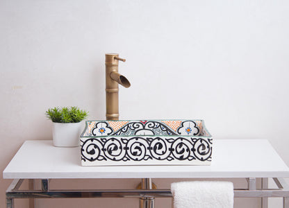 Side view of handmade rectangular ceramic sink showcasing ornate scrollwork border patterns in bathroom setting with bamboo-style faucet