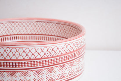 Macro close-up detail of intricate coral pink and white geometric pattern bands around the exterior rim of handcrafted ceramic basin