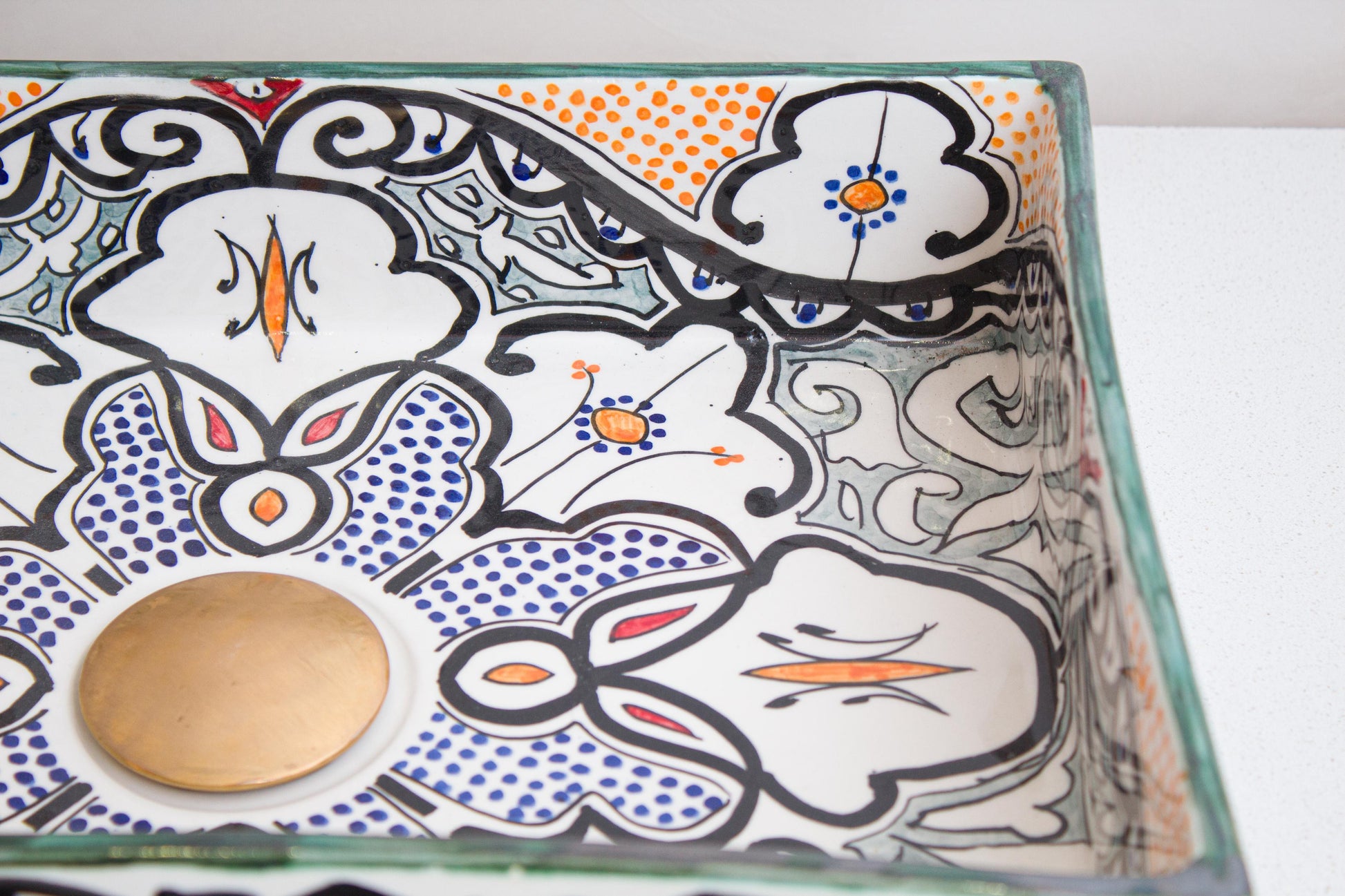 Close-up interior detail showing blue stippled floral medallion with orange accents and decorative geometric patterns inside ceramic bathroom basin