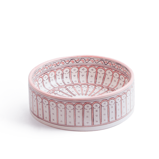 Three-quarter perspective view of handcrafted round ceramic basin featuring coral pink and white Moorish architectural arch motifs