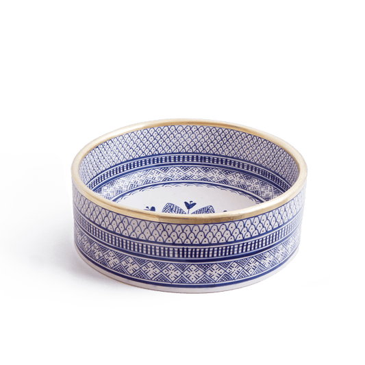 Three-quarter perspective view of handcrafted round ceramic basin featuring blue and white geometric patterns