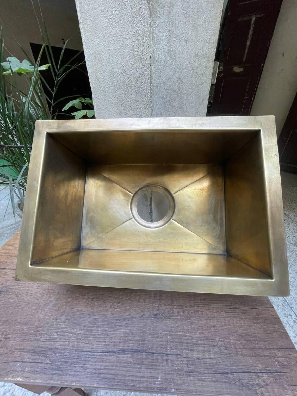 Brass kitchen sink on a wooden surface with a neutral background