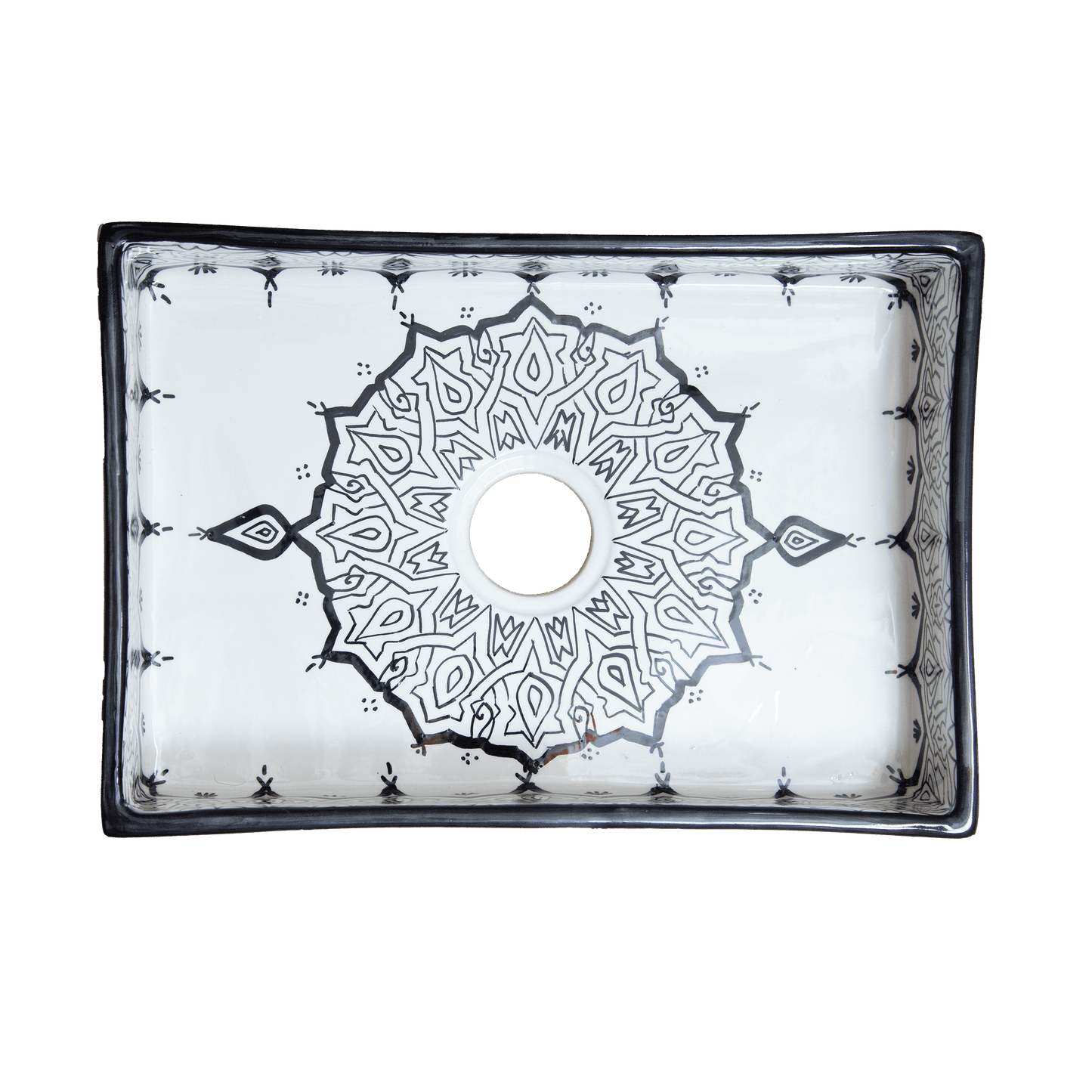 Top-down view of a handmade Moroccan rectangular ceramic bathroom sink, showcasing a central black geometric starburst pattern around the drain and a dark contrasting rim.