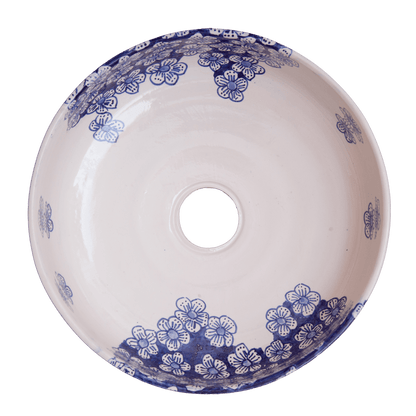 Top-down interior view of ceramic vessel sink displaying scattered blue floral motifs and clustered flower patterns with central drain opening