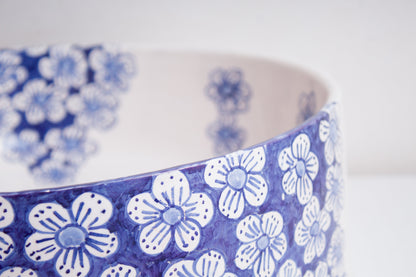 Close-up detail of ceramic vessel sink rim highlighting the hand-painted blue floral pattern and delicate flower motifs
