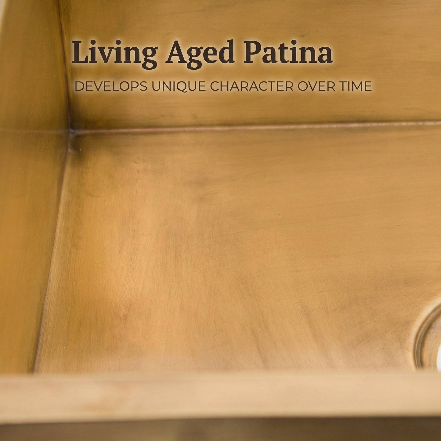 Close-up detail of the interior of a handmade aged brass undermount kitchen sink, showing the living patina finish with warm bronze tones, hand-welded seams, and the drain opening in the corner.