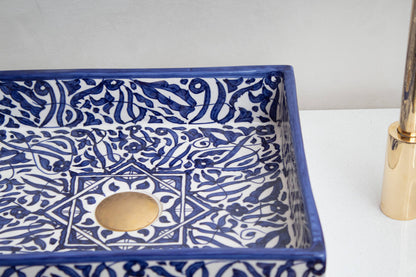 Interior view of handmade ceramic sink showing blue geometric pattern and central drain opening