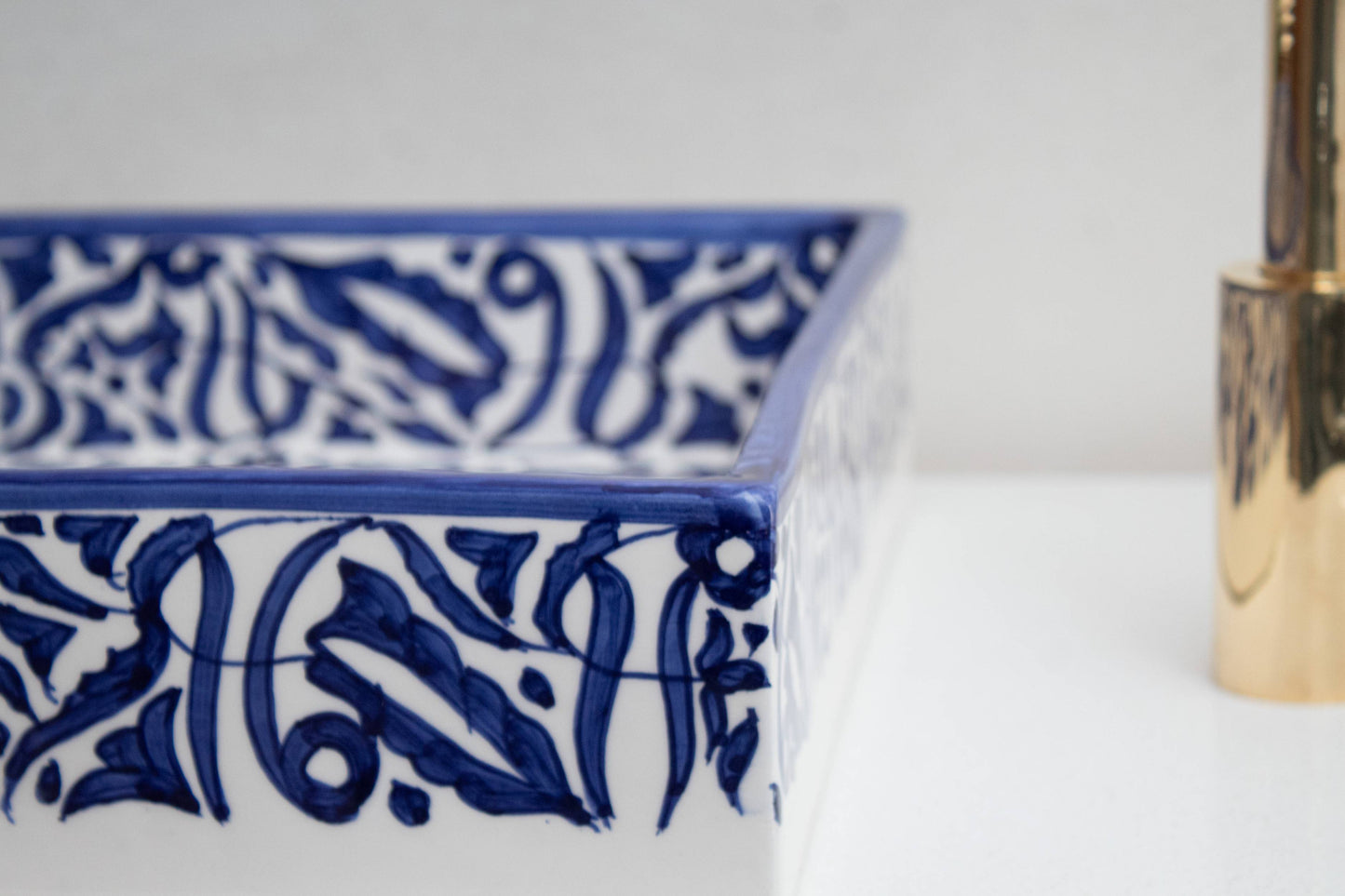 Close-up of hand-painted navy blue Moroccan pattern on glazed rim of ceramic bathroom sink