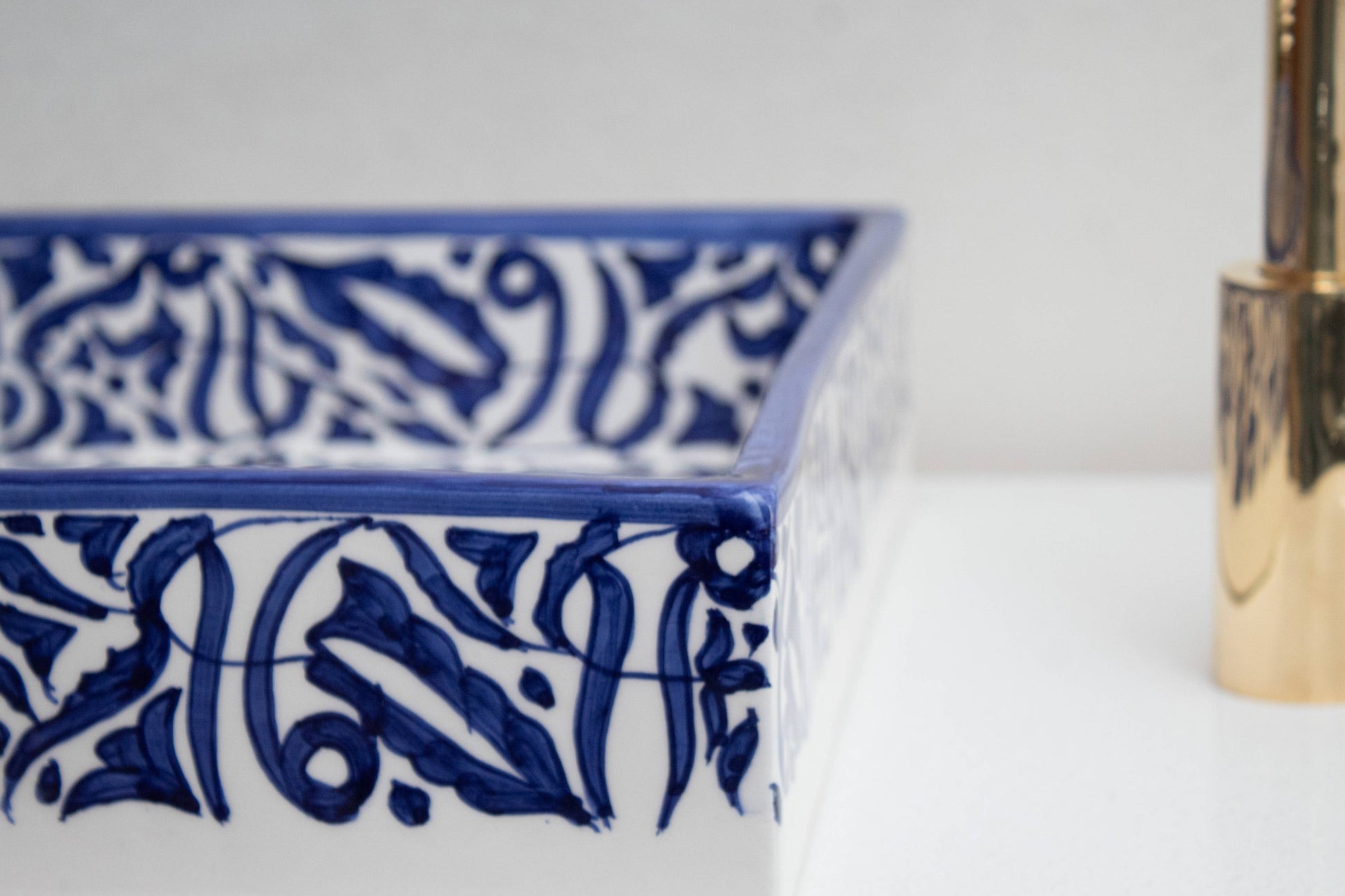 Close-up of hand-painted navy blue Moroccan pattern on glazed rim of ceramic bathroom sink
