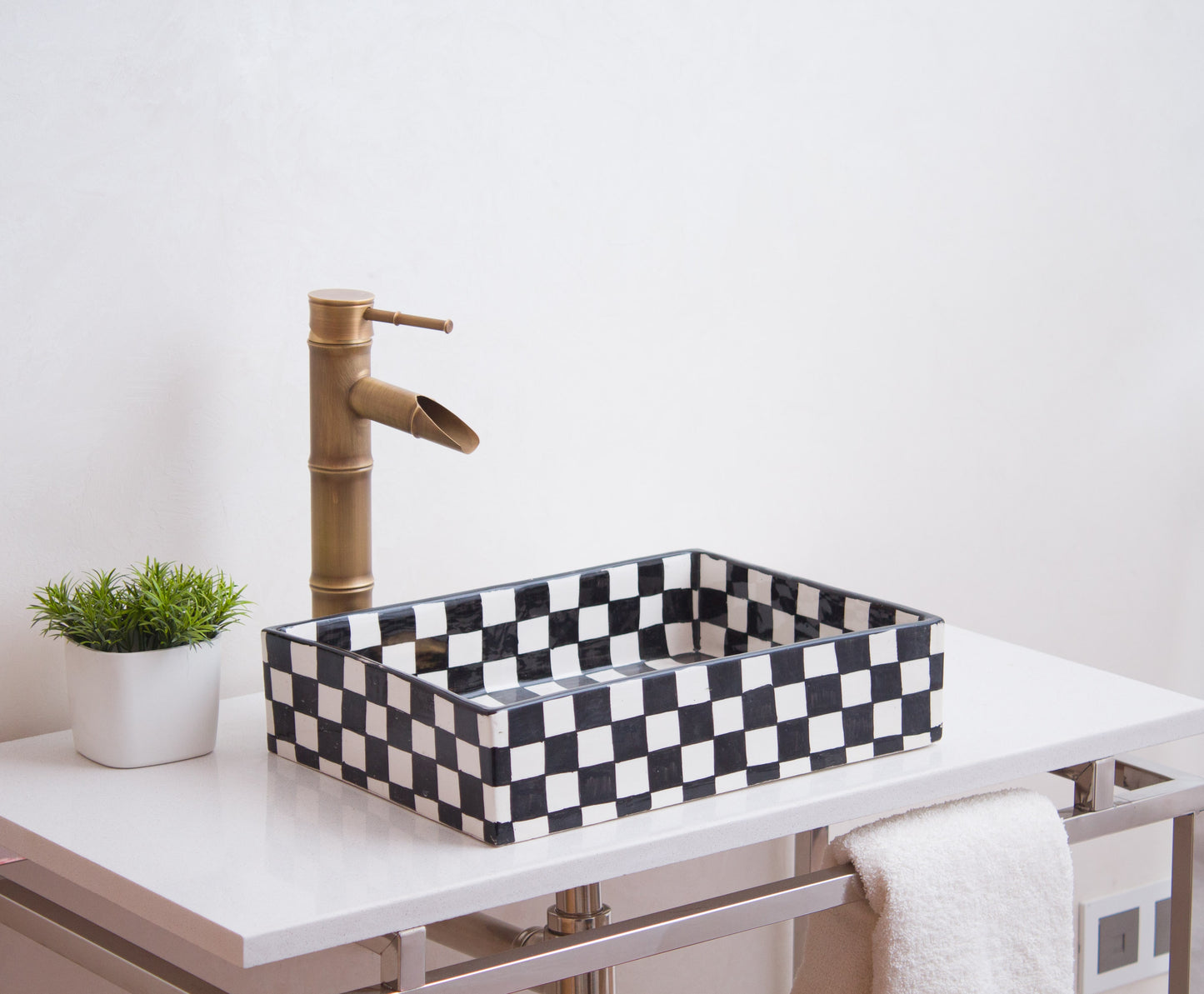 Black and white checkerboard ceramic basin styled with brass bamboo faucet on modern vanity