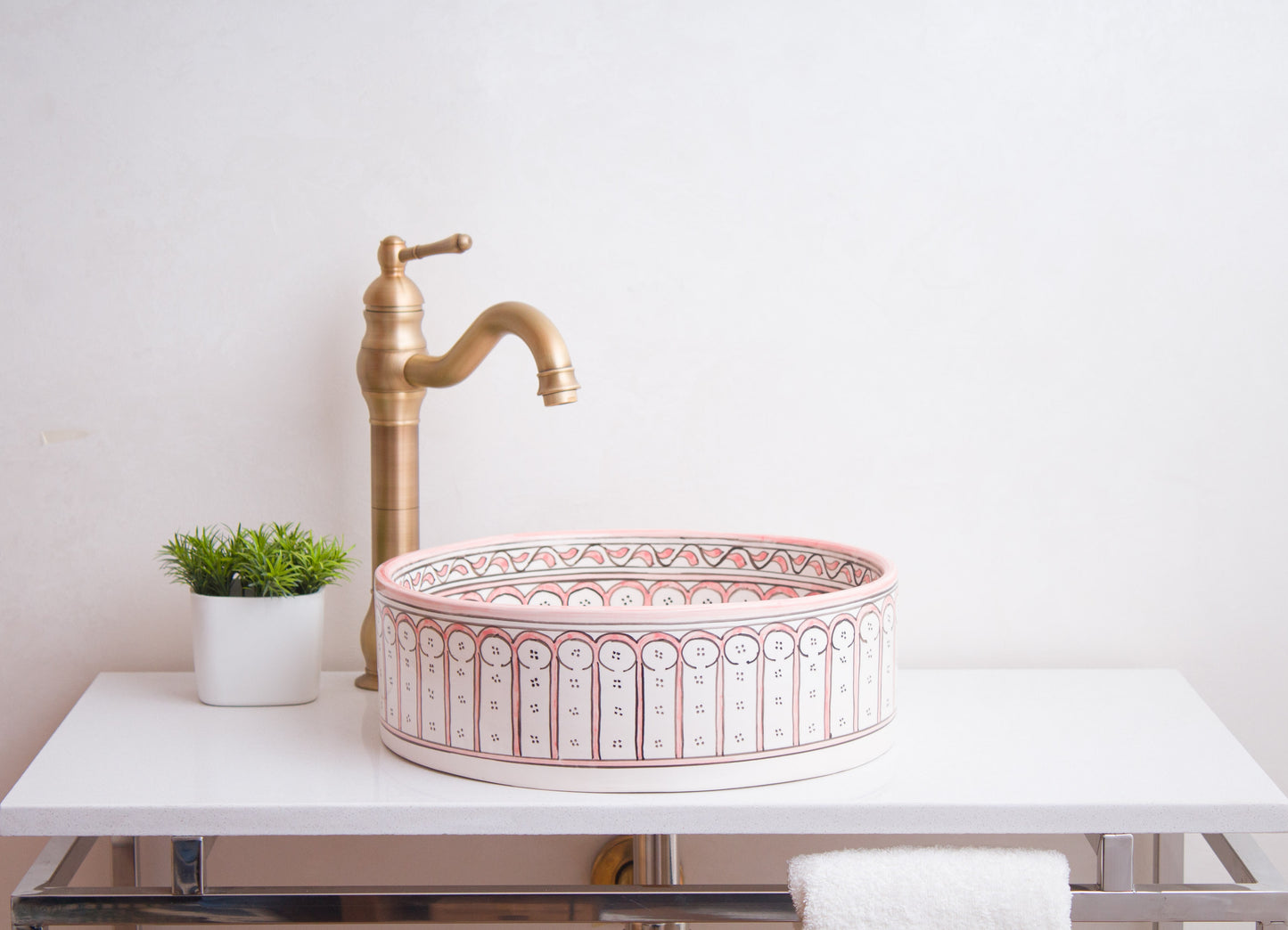 Side profile view of round ceramic vessel sink showing coral pink Moorish arch pattern bands and bathroom installation