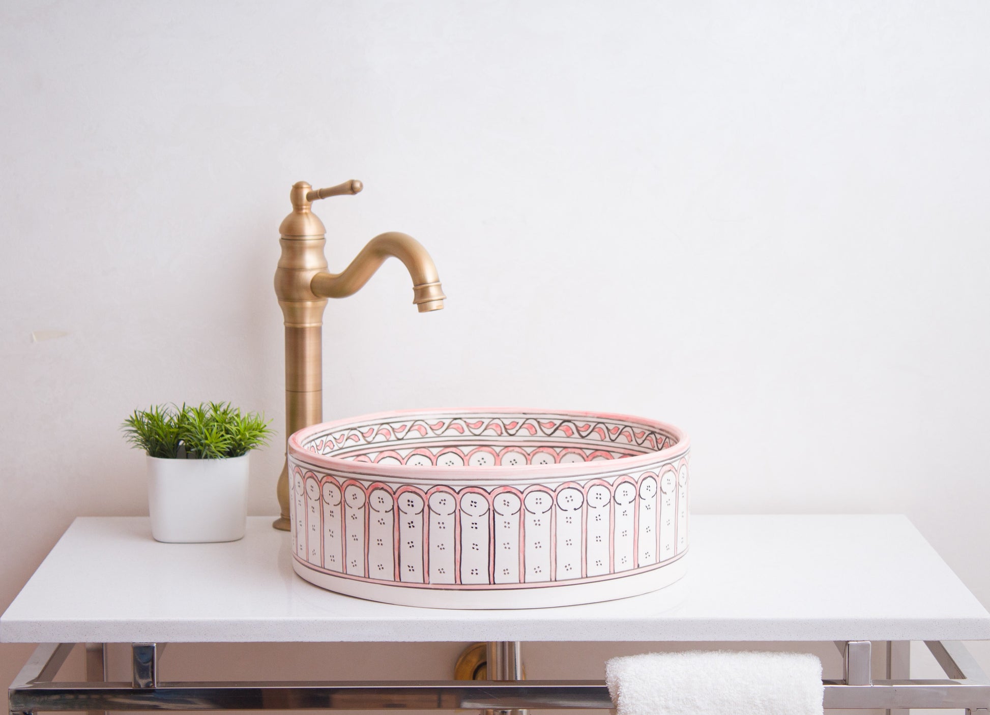 Side profile view of round ceramic vessel sink showing coral pink Moorish arch pattern bands and bathroom installation