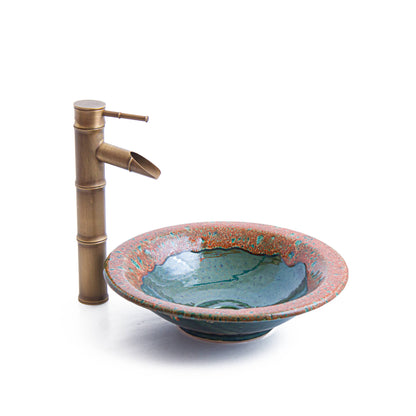 Three-quarter view of handmade ceramic vessel sink with footed base and decorative rim