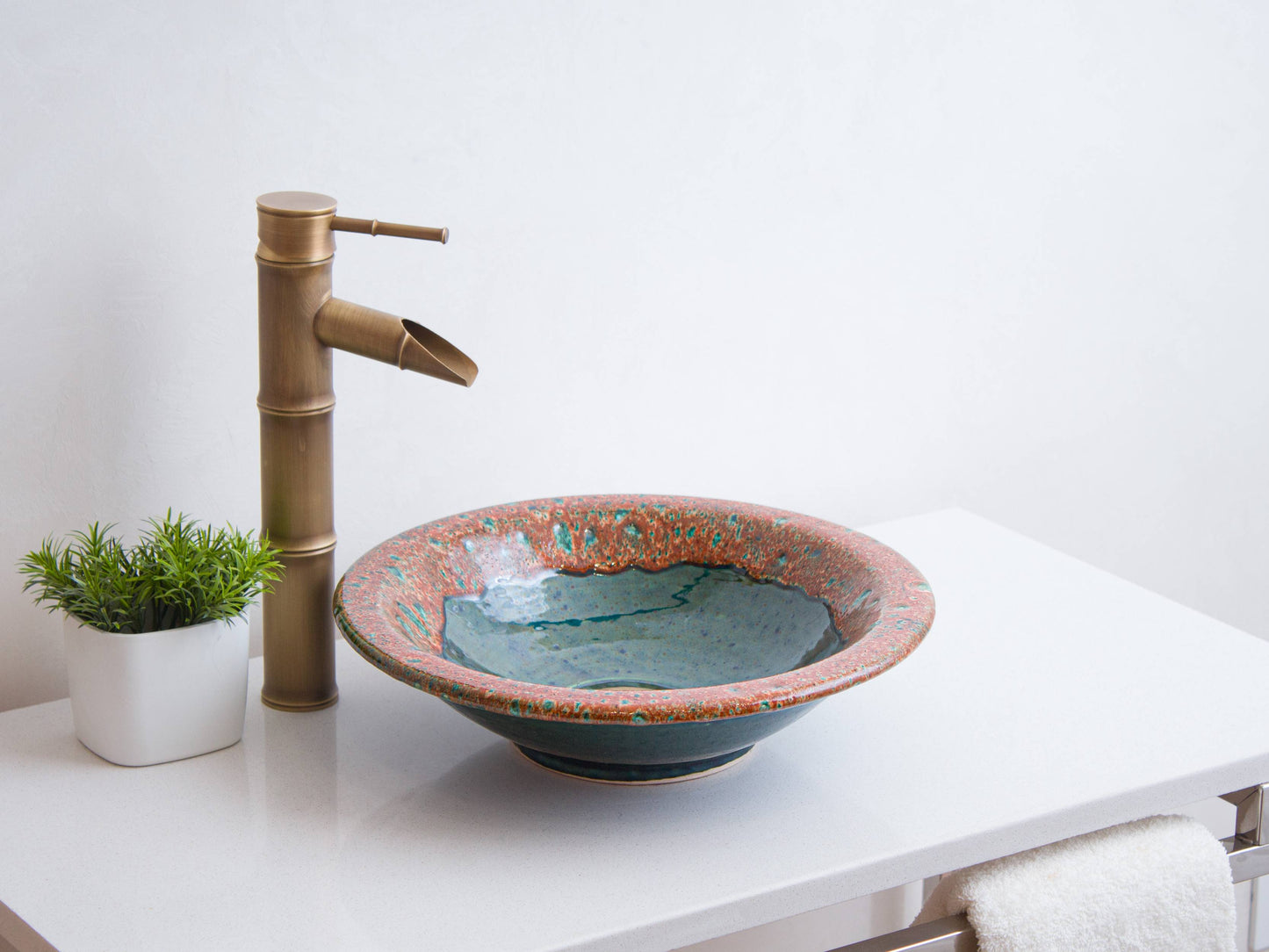 Handmade round ceramic vessel sink with turquoise speckled pattern on coral rim and teal interior bowl