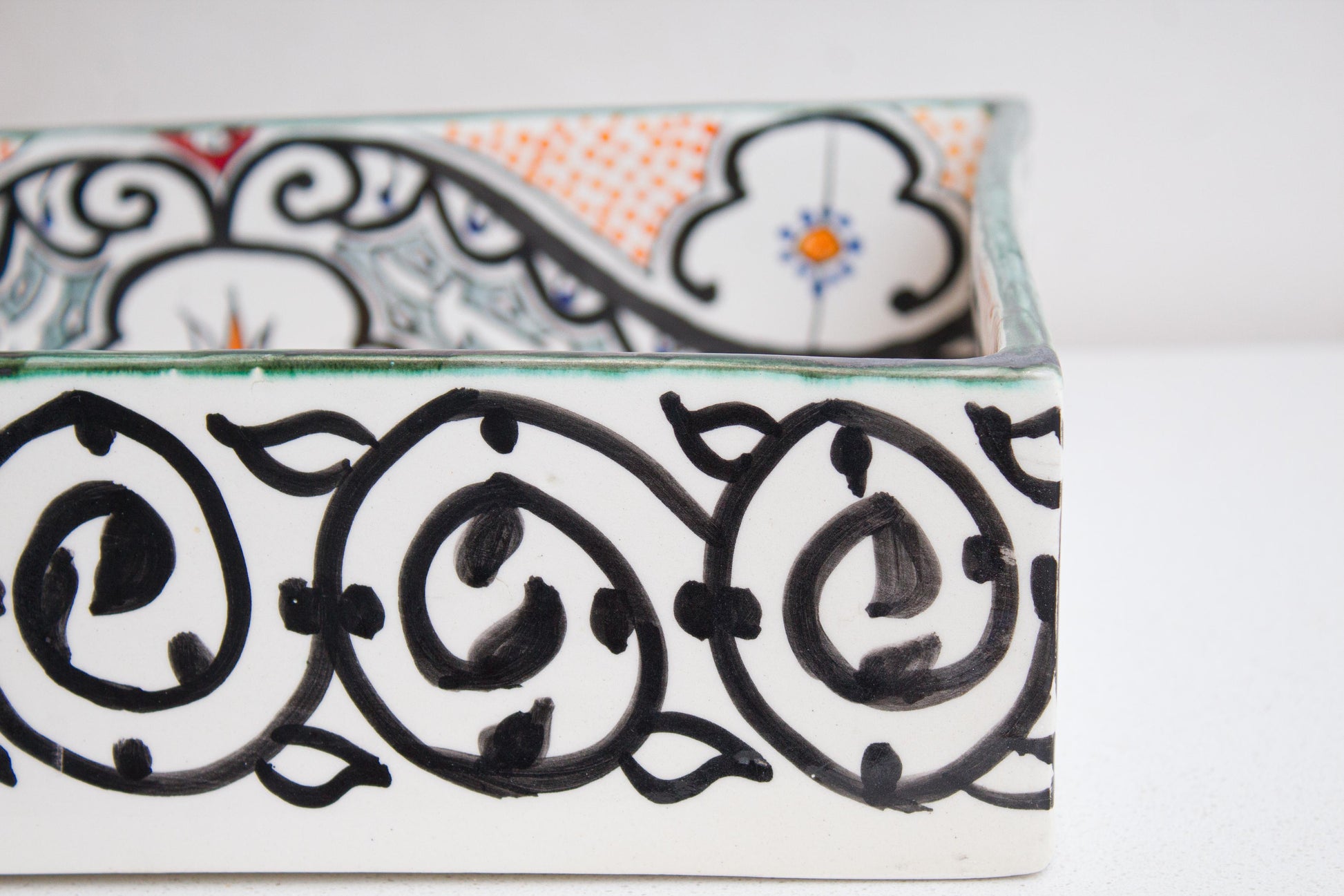 Detailed view of handpainted black scrollwork border pattern on exterior wall of artisan-crafted Moroccan ceramic vessel sink
